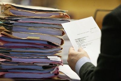 advogado lendo documento com pilha de processos sobre a mesa