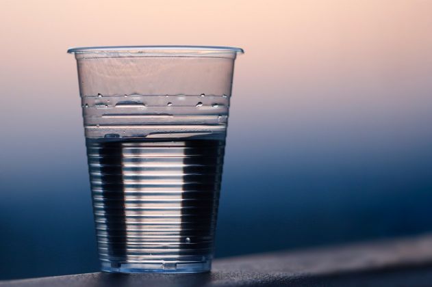 copo plástico com água em superfície azul