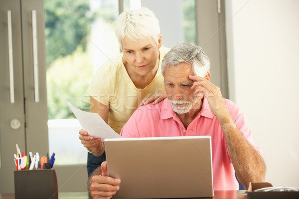 casal de idosos lendo notícia em notebook