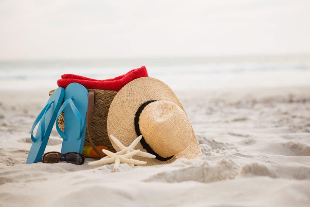 chapéu bolsa e chinelo de dedo na areia da praia