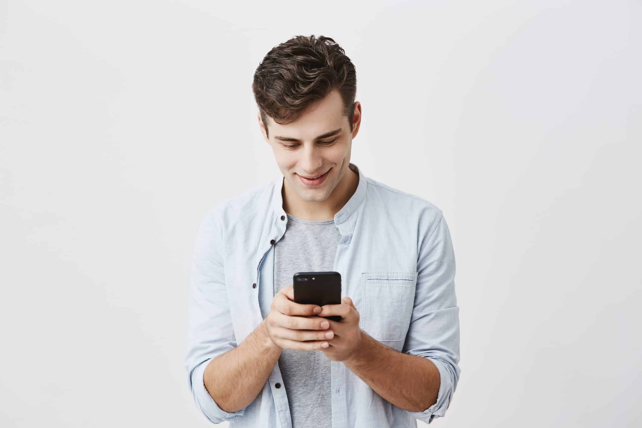 jovem de camisa azul sobre camiseta lendo no celular