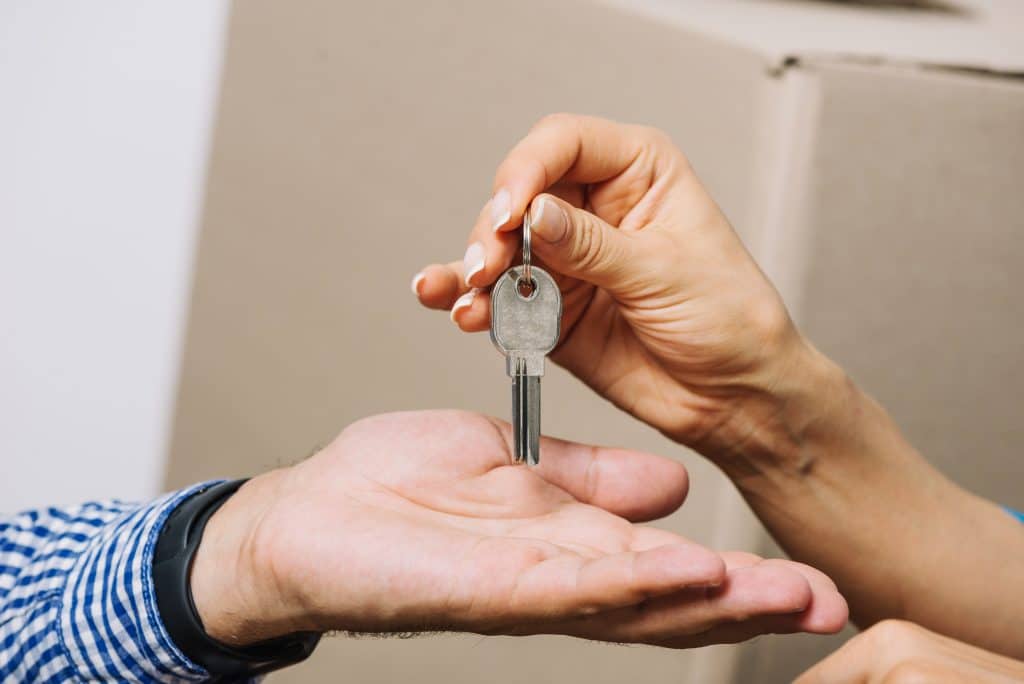 mão de anfitrião de airbnb entregando chaves de imóvel na mão do hóspede