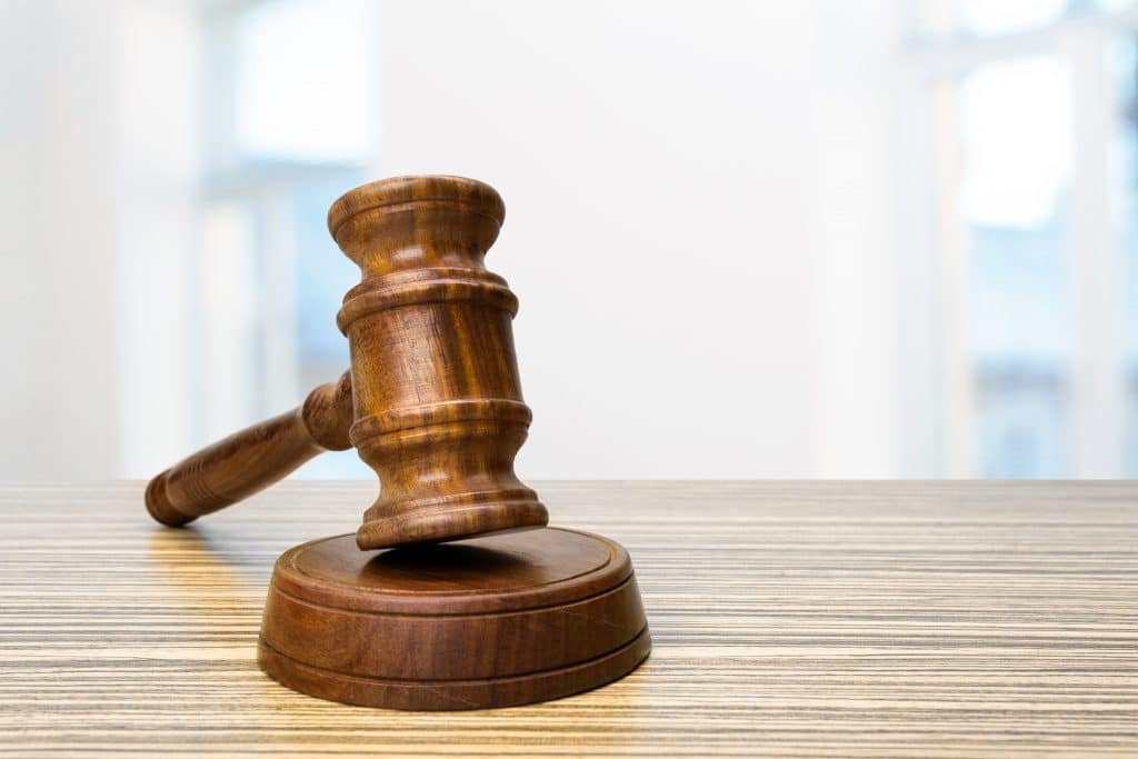 Martelo marrom de juiz sobre sobre tampo de mesa de escritório em fórmica com ranhuras marrom clara em fundo desfocado azul claro