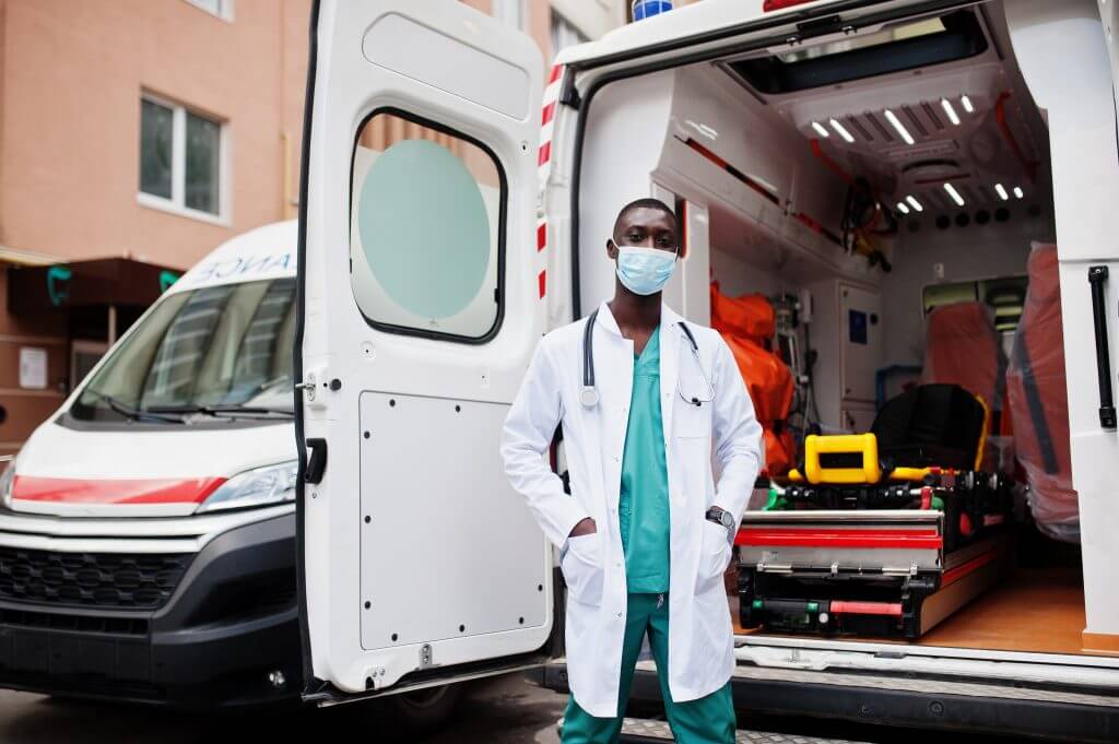 medico na frente de ambulância com portas abertas