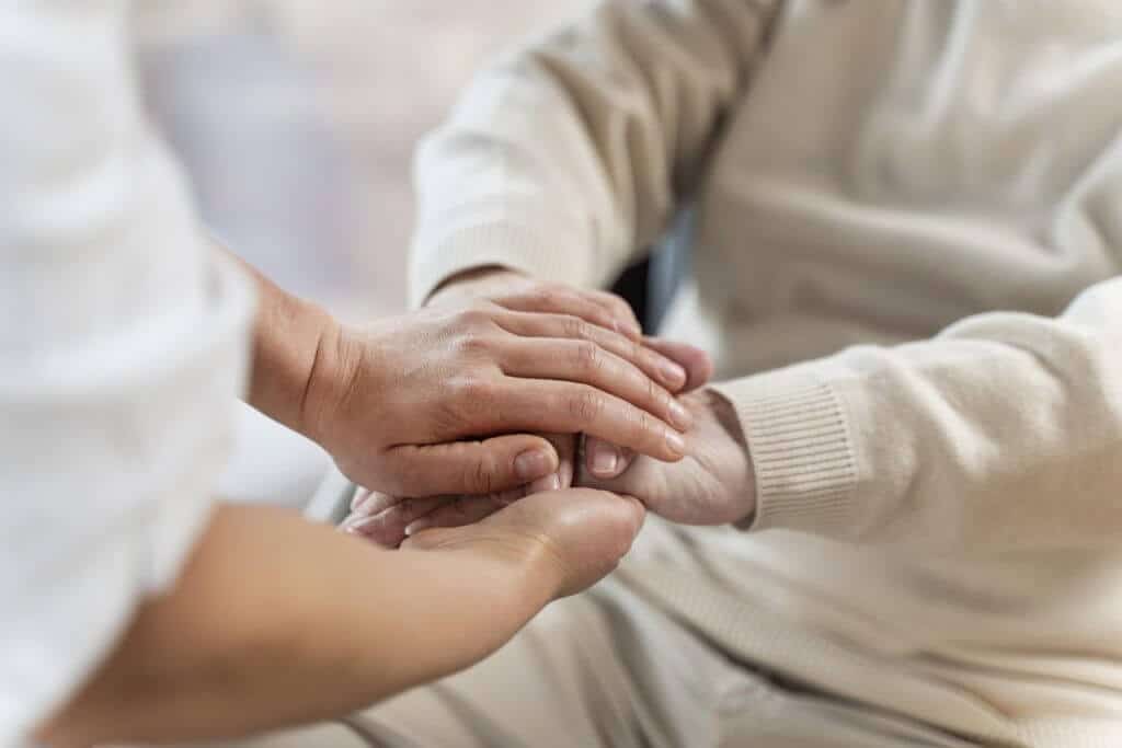 médico segurando mãos de idosa