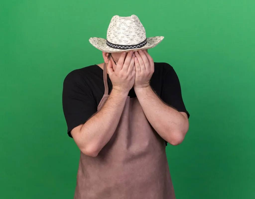 agricultor de chapéu de palha com as mãos escondendo o rosto