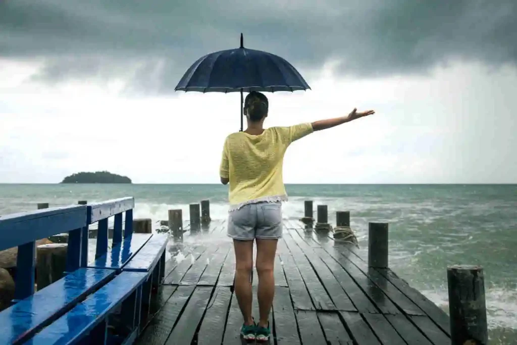 garota de guarda-chuva à beira do mar